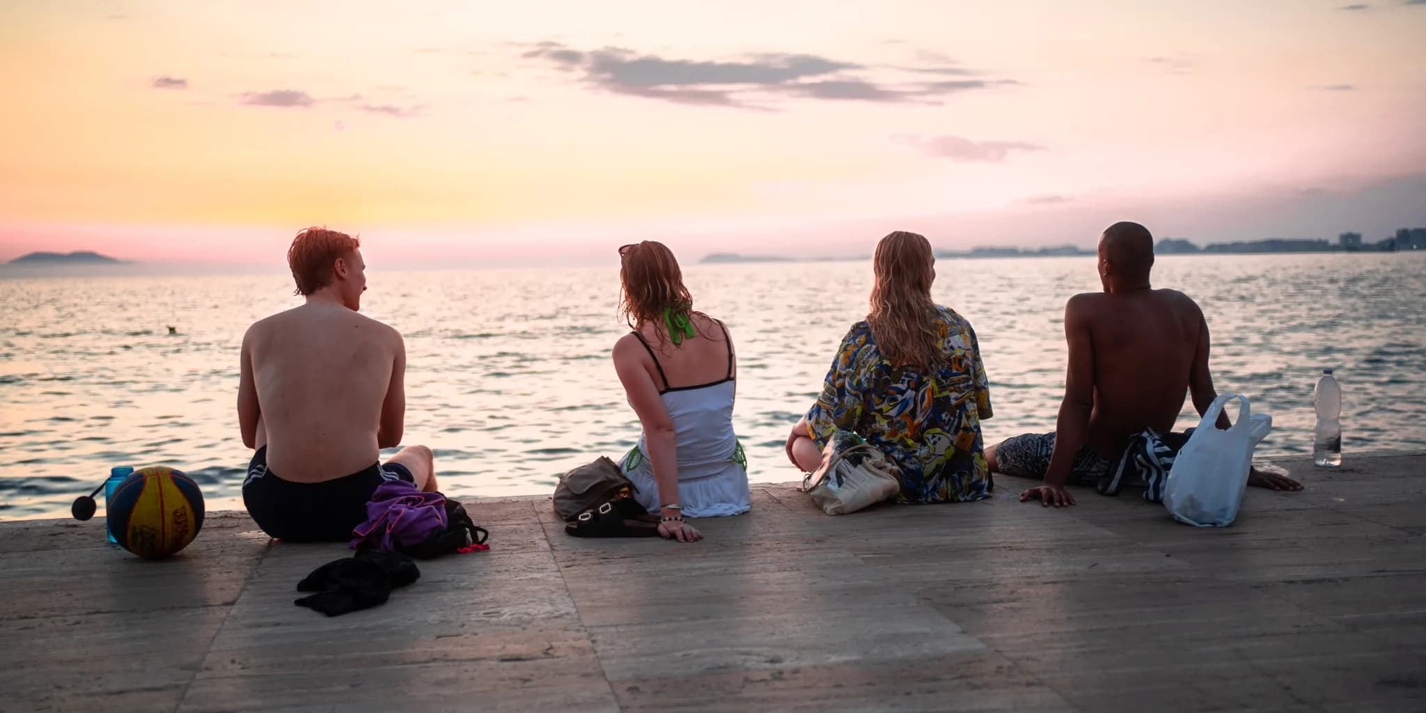 Friends sitting at the seaside at sunset