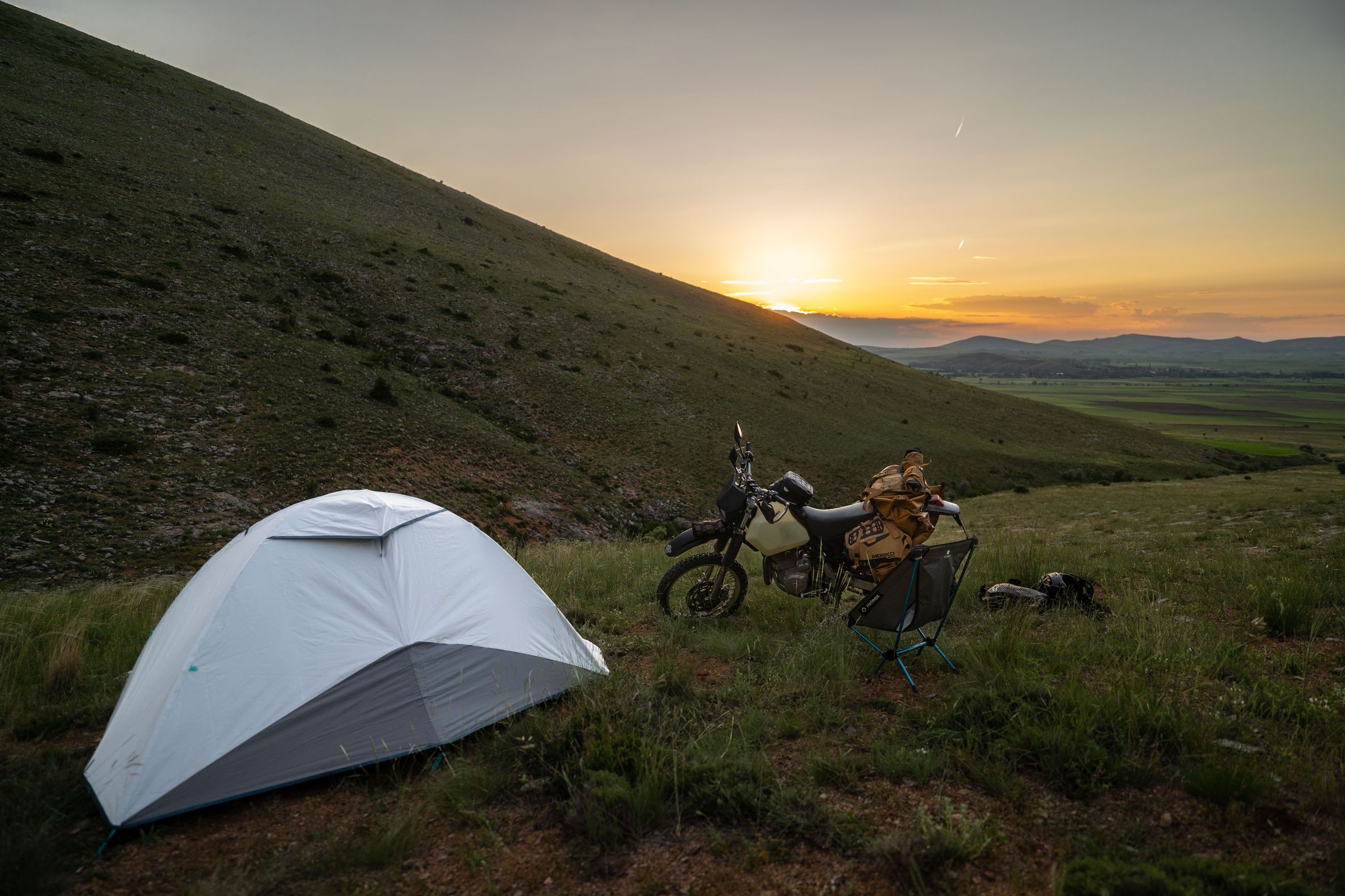 Wild camp at sunset in the Turkish mountains — tent, camp chair and the Suzuki DR650 SE